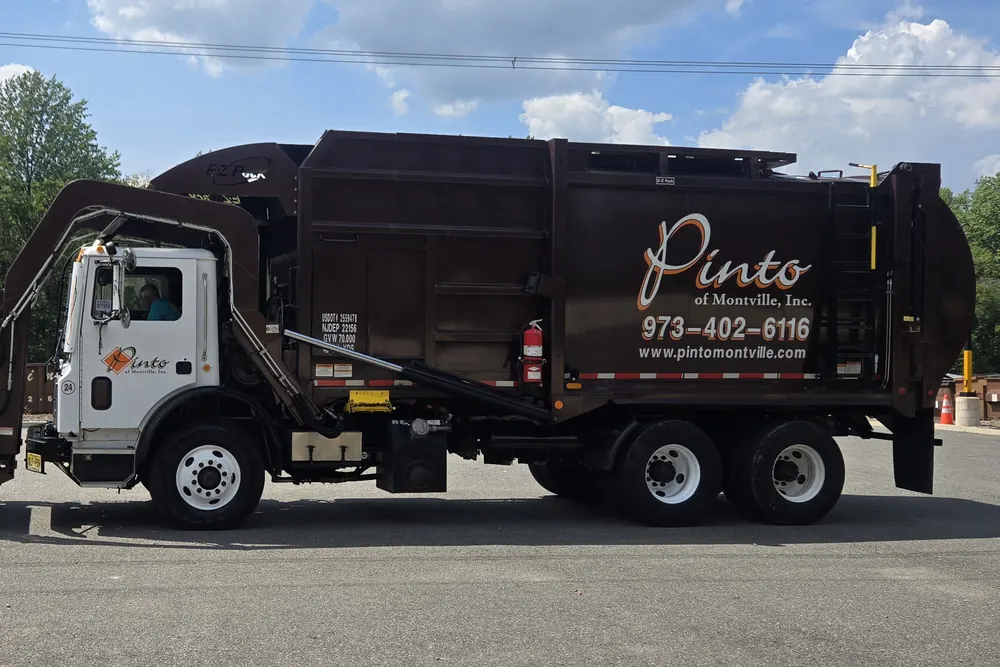 A Pinto of Montville front-load refuse truck with a commercial container on its forks
