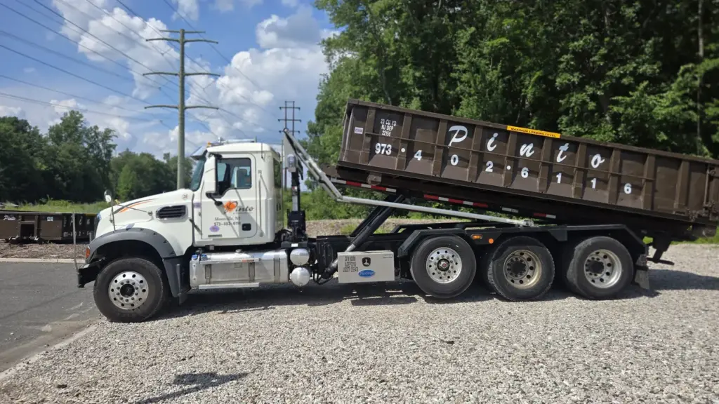 A Pinto of Montville roll-off truck lowering a container at the company yard