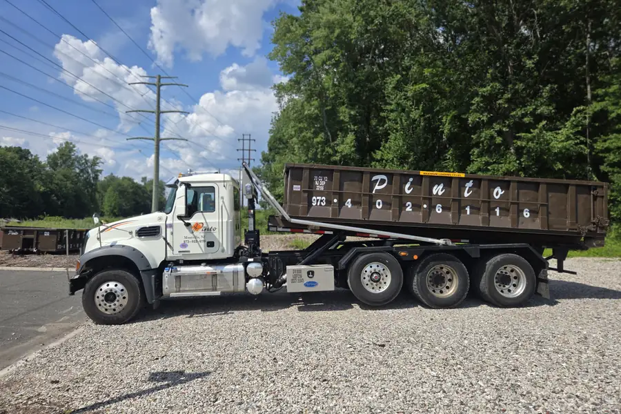 A Pinto of Montville roll-off truck with a dumpster loaded for removal