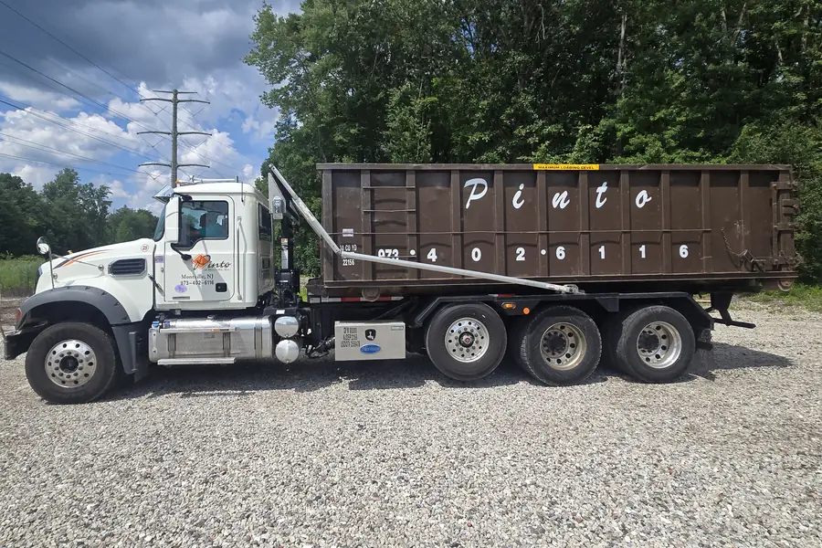 A Pinto of Montville roll-off truck carrying a 30-yard container