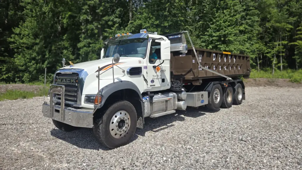 A Pinto of Montville roll-off truck carrying a container, seen from the front quarter
