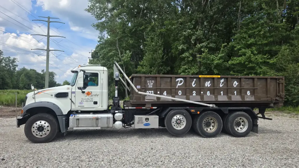 A Pinto of Montville roll-off truck carrying a 20-yard container